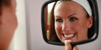 woman looking at teeth in mirror 200x100 - چرا از دیدن عکس خود نفرت داریم